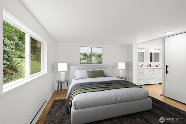 bedroom with baseboard heating, light wood-style flooring, ensuite bathroom, and baseboards