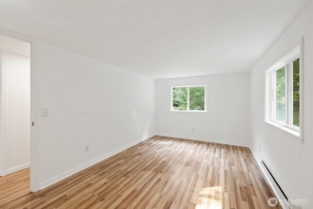 unfurnished room featuring light wood-style flooring, a baseboard heating unit, and baseboards