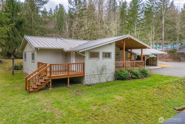 view of front of property featuring a wooden deck, a front lawn, and metal roof