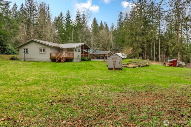 view of yard featuring a forest view, an outbuilding, and a shed