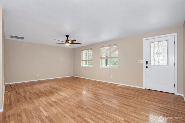 foyer entrance with visible vents, ceiling fan, baseboards, and light wood-style floors