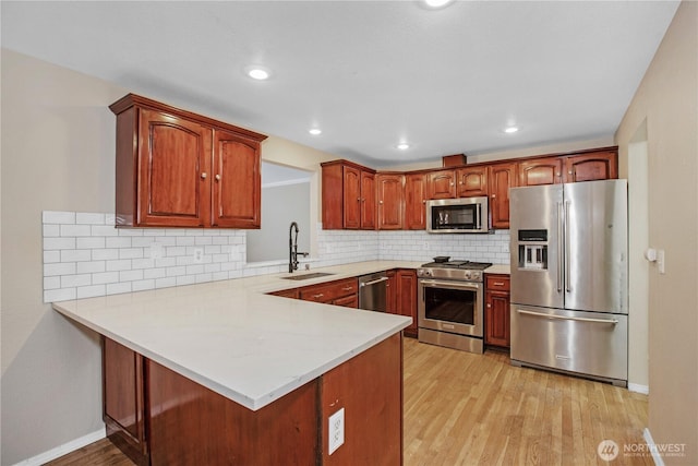 kitchen featuring light countertops, light wood-style floors, appliances with stainless steel finishes, and a sink