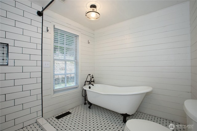 bathroom with tile patterned floors, visible vents, toilet, a tile shower, and a freestanding bath