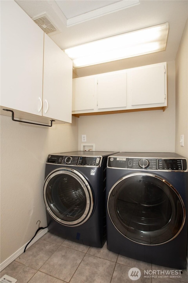 laundry area featuring light tile patterned floors, cabinet space, visible vents, and washing machine and clothes dryer