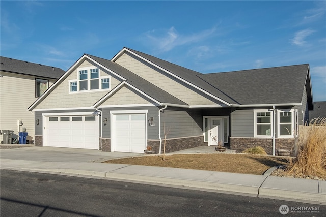 craftsman inspired home with concrete driveway, an attached garage, and stone siding