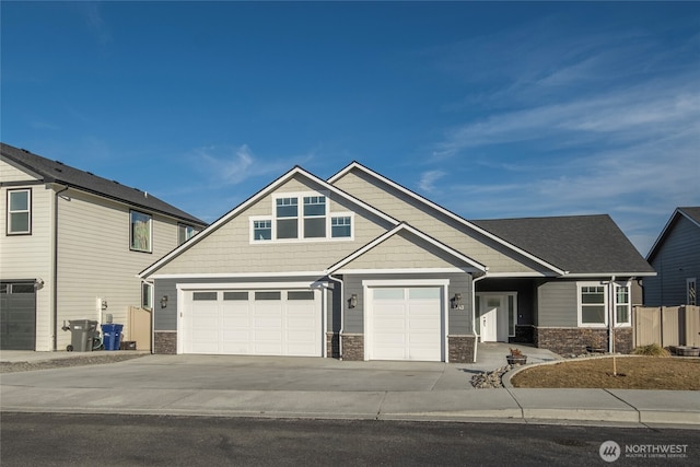 craftsman inspired home with a garage, stone siding, and driveway