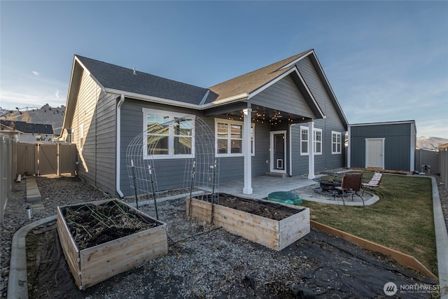 back of property with a storage shed, a fenced backyard, an outdoor structure, a patio area, and a vegetable garden