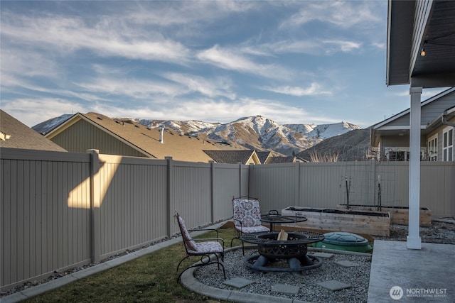 view of yard featuring a fenced backyard, a mountain view, and an outdoor fire pit