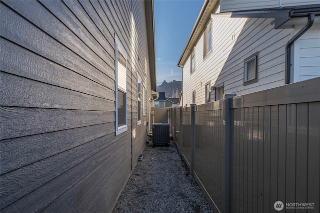 view of side of home with cooling unit and fence