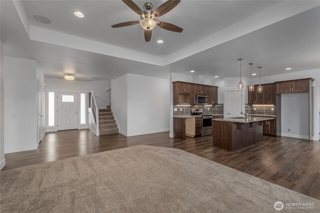 kitchen with a kitchen island with sink, open floor plan, appliances with stainless steel finishes, and a sink