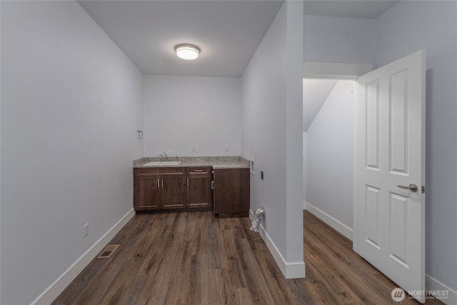 laundry room featuring dark wood finished floors, visible vents, baseboards, and a sink