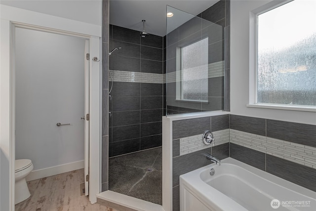 full bath with a garden tub, wood finished floors, toilet, and a tile shower