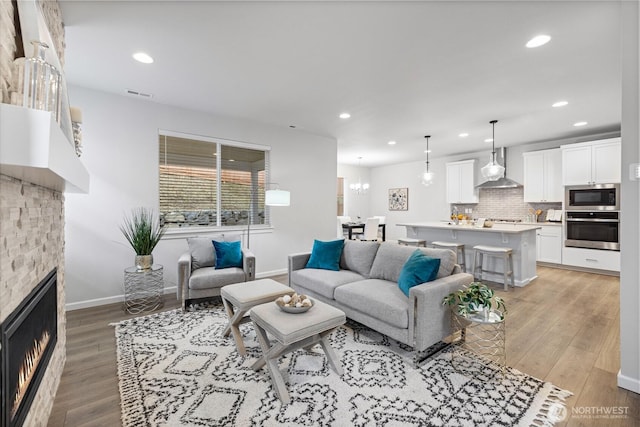 living area with recessed lighting, visible vents, light wood finished floors, and a lit fireplace