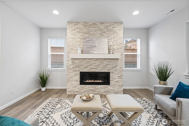 living area featuring wood finished floors, visible vents, a wealth of natural light, and baseboards