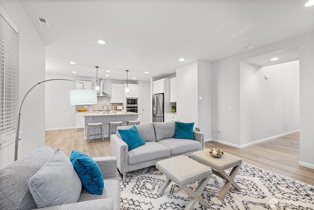 living room featuring recessed lighting, light wood-type flooring, baseboards, and visible vents