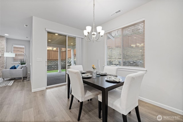 dining area featuring an inviting chandelier, light wood-style flooring, baseboards, and visible vents