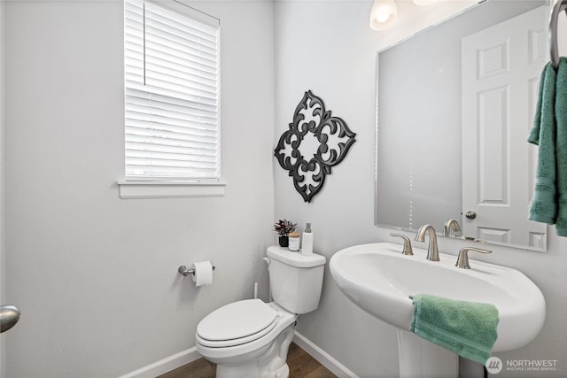 bathroom with toilet, wood finished floors, baseboards, and a sink