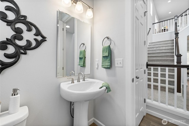 half bathroom featuring toilet, wood finished floors, and baseboards