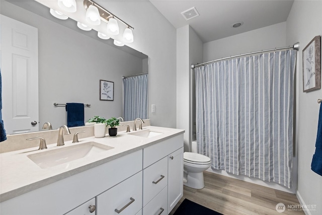 full bathroom featuring visible vents, toilet, wood finished floors, and a sink