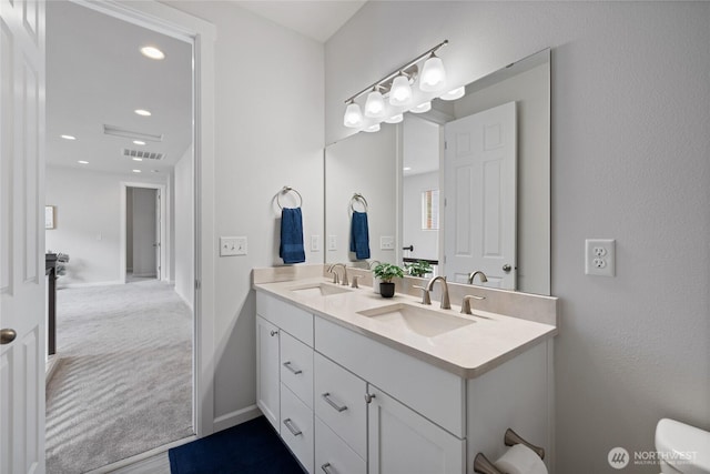 full bath featuring double vanity, visible vents, toilet, and a sink