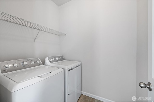 laundry area with laundry area, washer and dryer, baseboards, and light wood-style floors