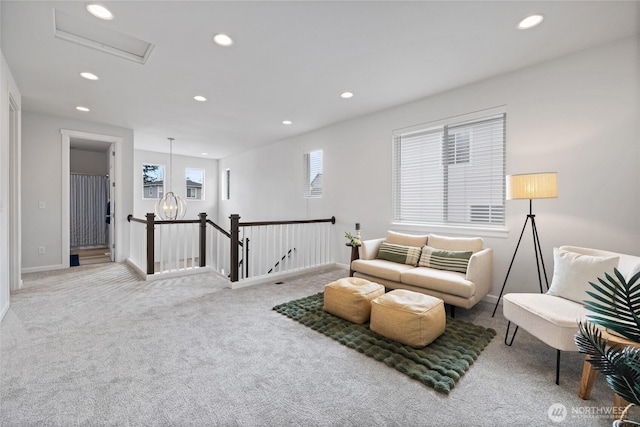 living area with an upstairs landing, recessed lighting, carpet floors, baseboards, and attic access