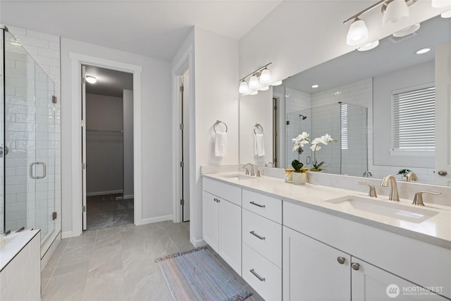 bathroom featuring a sink, baseboards, a spacious closet, and a shower stall