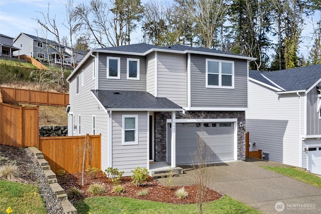 traditional-style home featuring fence, driveway, a shingled roof, stone siding, and a garage