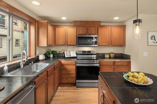 kitchen with brown cabinets, a sink, recessed lighting, appliances with stainless steel finishes, and light wood finished floors