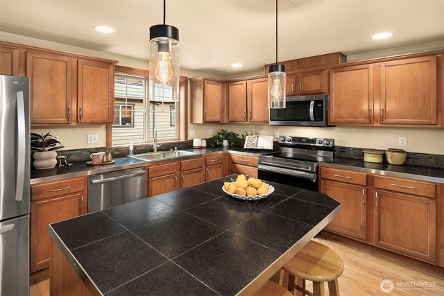 kitchen featuring a sink, a kitchen breakfast bar, brown cabinetry, and stainless steel appliances