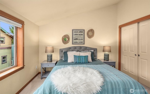 carpeted bedroom featuring a closet, lofted ceiling, and baseboards