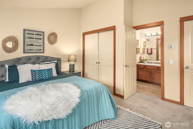 bedroom featuring baseboards, a sink, a closet, light carpet, and connected bathroom