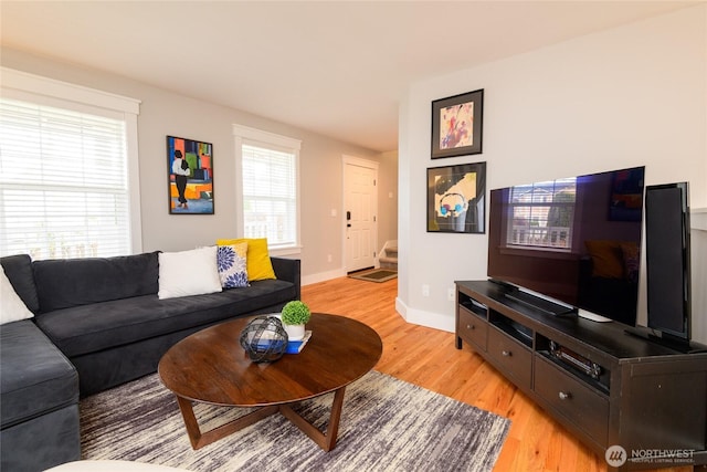 living room featuring light wood-type flooring, baseboards, and a healthy amount of sunlight