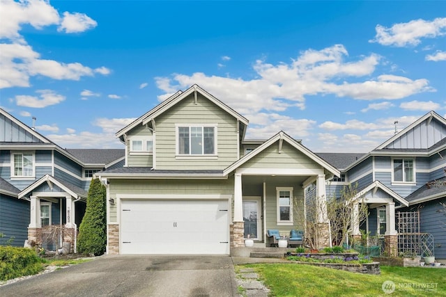 craftsman house with board and batten siding, driveway, stone siding, and a garage