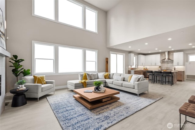 living area featuring a tiled fireplace, a healthy amount of sunlight, and light wood-style floors