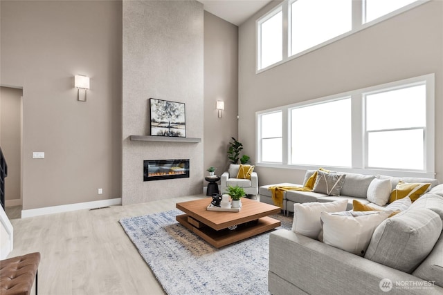 living area with baseboards, plenty of natural light, wood finished floors, and a fireplace