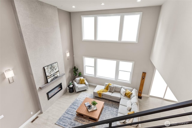 living room with visible vents, plenty of natural light, a towering ceiling, and a tiled fireplace