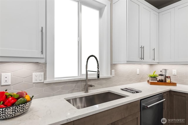 kitchen featuring dishwasher, white cabinets, backsplash, and a sink