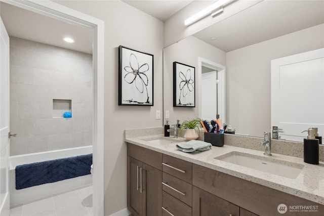 full bathroom with double vanity, tile patterned floors, tiled shower, and a sink