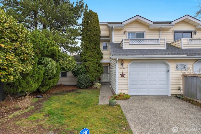 multi unit property featuring an attached garage, a front yard, roof with shingles, and driveway