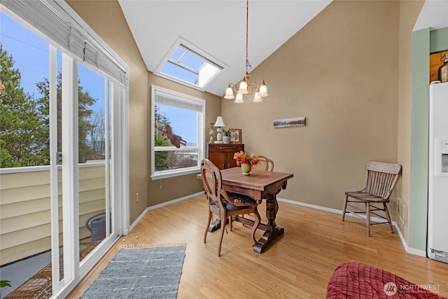 dining space featuring vaulted ceiling, a notable chandelier, wood finished floors, and baseboards