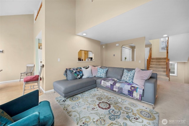 living area featuring baseboards, a towering ceiling, and stairs