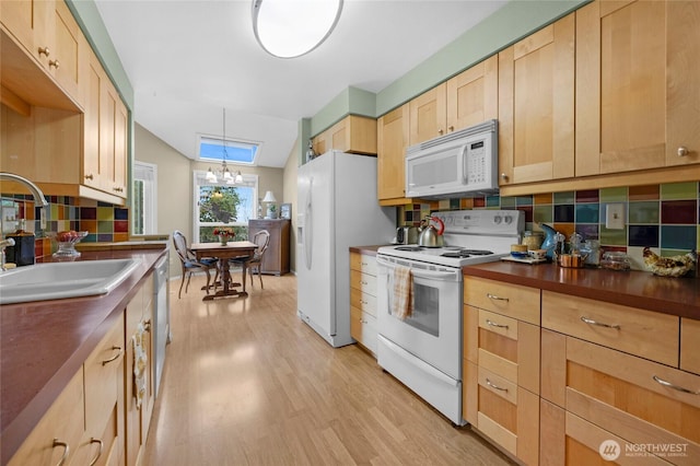 kitchen with a notable chandelier, light wood-style flooring, light brown cabinetry, a sink, and white appliances