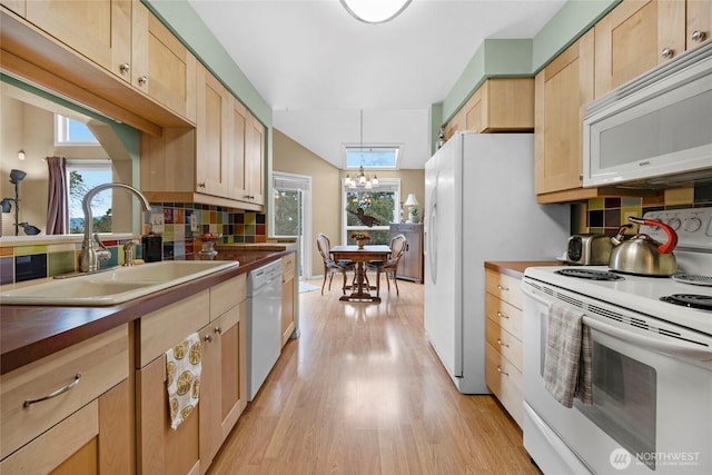 kitchen with white appliances, dark countertops, light brown cabinetry, and a sink