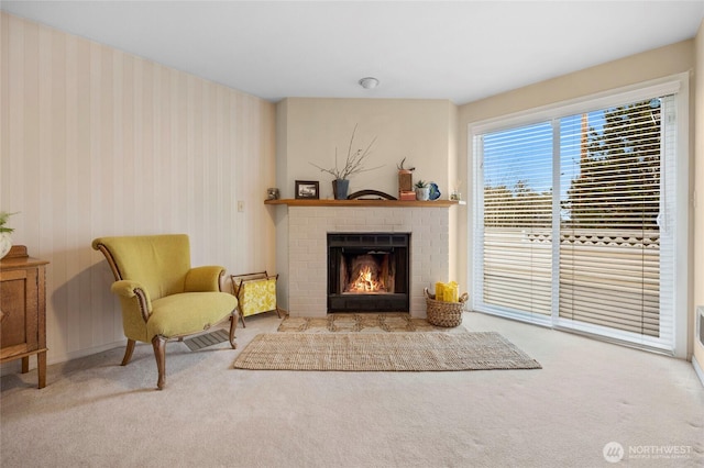 sitting room featuring baseboards, carpet floors, a fireplace, and wallpapered walls