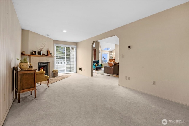 sitting room with recessed lighting, a fireplace, arched walkways, and light carpet