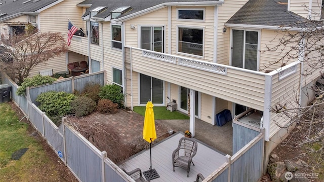 back of property with a fenced backyard, roof with shingles, and a wooden deck