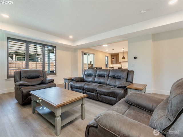 living area with recessed lighting, baseboards, and light wood-style flooring