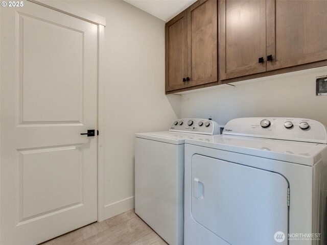 clothes washing area featuring cabinet space, baseboards, and separate washer and dryer