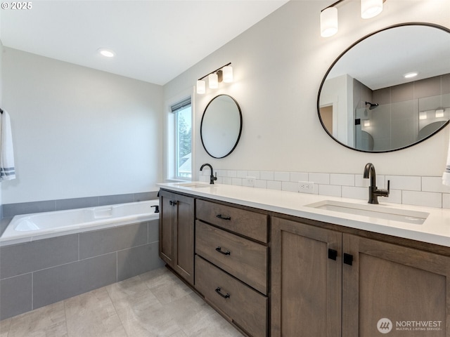 full bath with a garden tub, double vanity, tasteful backsplash, and a sink